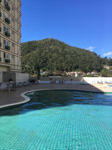 a swimming pool in front of a building with a mountain at Granja Brasil in Itaipava