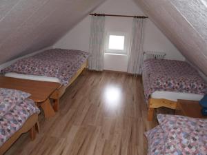 a attic room with two beds and a table at Penzion Kuba in Smržovka