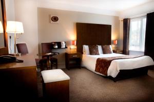 ein Hotelzimmer mit einem großen Bett und einem Schreibtisch in der Unterkunft The Gateway Hotel in Swinford
