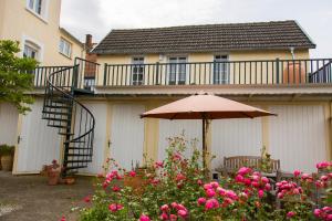 eine Terrasse mit einem Sonnenschirm und rosa Blumen in der Unterkunft Room 68 in Friedberg