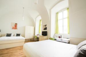 a white bedroom with two beds and a window at myNext - Johannesgasse Apartments in Vienna