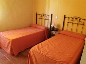 dwa łóżka w pokoju z pomarańczową pościelą w obiekcie Apartamentos las Fuentes del Alto Tajo w mieście Peralejos de las Truchas