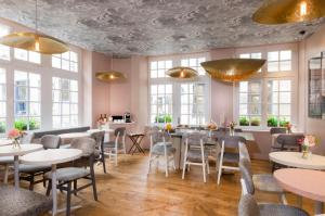 a restaurant with tables and chairs and windows at Hôtel Jeanne d'Arc Le Marais in Paris