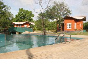ein Schwimmbad mit einem Haus im Hintergrund in der Unterkunft Ritigala Lodge in Habarana
