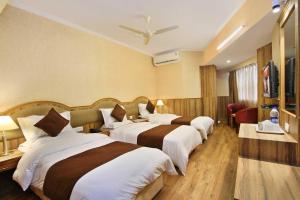 Habitación de hotel con 3 camas y TV en Empire International Church Street en Bangalore
