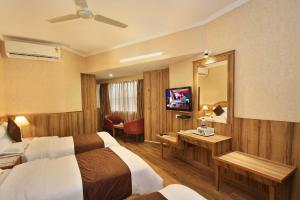 a hotel room with two beds and a mirror at Empire International Church Street in Bangalore