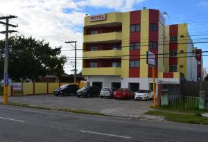 un hotel con coches estacionados en un estacionamiento en Arpini Hotel, en Río Grande