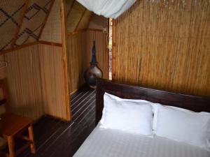 1 dormitorio con 1 cama con almohadas blancas en Rwiza Village, en Gitesi