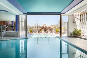 a swimming pool in a building with a view of the city at Coast Victoria Hotel & Marina by APA in Victoria