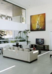 uma sala de estar branca com um sofá e uma televisão em H Ponta Negra Beach - Luxo em Natal
