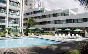 un hotel con una piscina con sillas y sombrillas en H Ponta Negra Beach - Luxo, en Natal