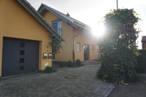 una casa con el sol brillando detrás de un árbol en Ferienwohnung Heldenfingen, en Heldenfingen