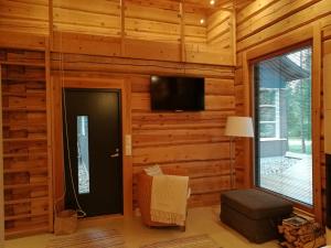Zimmer mit einer Holzwand, einer Tür und einem TV in der Unterkunft Syöte Cottage in Syöte