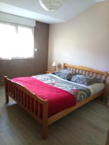 a bedroom with a wooden bed with a red blanket at Les logis de Lucie in Selonnet