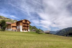 um edifício numa colina com um campo verde em Ciasa Medalghes em San Martino in Badia