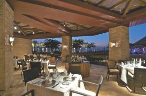 a restaurant with white tables and chairs on a patio at Mövenpick Resort & Spa Tala Bay Aqaba in Aqaba