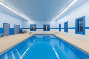 a swimming pool in a building with blue walls at Super 8 by Wyndham Devils Lake in Devils Lake