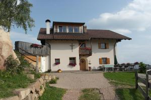 a white house with a balcony and a table at Oberfahrerhof in San Genesio Atesino