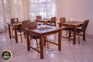 grupa drewnianych stołów i krzeseł w pokoju w obiekcie The Palace Guest House w mieście Harare