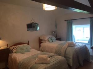 a bedroom with two beds and a tv on the wall at White Cottage Askham in Askham