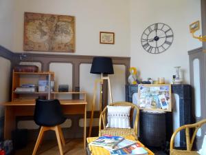 a room with a desk and a chair and a clock at L'Ajoussienne in Ajou
