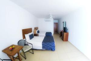 1 dormitorio con cama, mesa y TV en Costa Alegre Hotel & Suites en Rincón de Guayabitos
