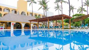 una piscina en el complejo con sillas y sombrillas en Costa Alegre Hotel & Suites, en Rincón de Guayabitos