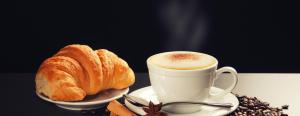 a cup of coffee and a croissant on a table at Guglielmo Marconi House in Rome
