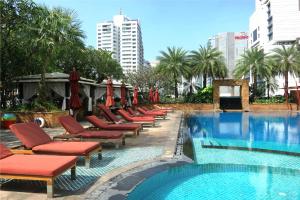 a pool with chaise lounge chairs and a row of hotels at Sky Villas Apartments in Bangkok