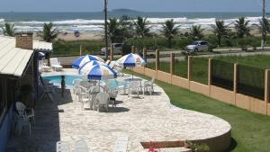 a patio with chairs and umbrellas next to a pool at Pousada Praia da Villa in Imbituba