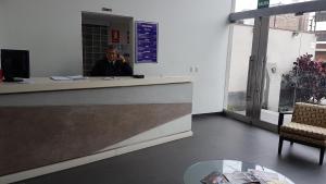 Ein Mann, der an einer Theke sitzt und auf einem Handy redet. in der Unterkunft Lima Flats 3 in Lima
