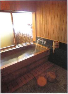 a bathroom with a bath tub with a window at Ise Todaya Ryoan in Ise