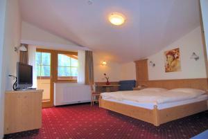 a bedroom with a bed and a television in it at Hotel Garni Forelle in Tux