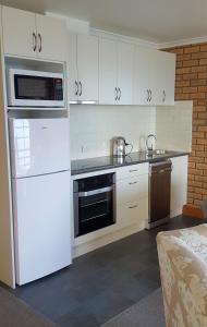 a kitchen with white cabinets and white appliances at Stanley Village Waterfront Accommodation in Stanley