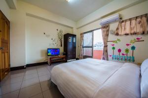 Un dormitorio con una cama y un televisor. en Happy Garden Homestay, en Taitung