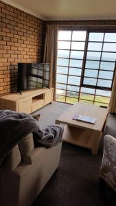 a living room with a couch and a television at Stanley Village Waterfront Accommodation in Stanley