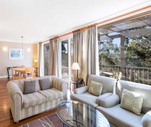 a living room with two couches and a glass table at Oaks Cypress Lakes Resort in Pokolbin