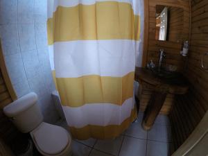 baño con cortina de ducha amarilla y blanca en Cabañas Piremapu, en Las Trancas