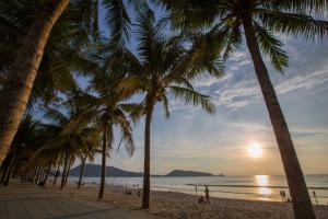 a group of palm trees on the beach at sunset at Magnific Guesthouse Patong in Patong Beach