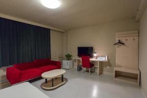 ein Wohnzimmer mit einem roten Sofa und einem Tisch in der Unterkunft Jinjiang Inn Beijing Olympics Park in Peking