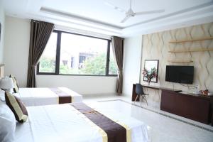 Habitación de hotel con 2 camas y TV de pantalla plana. en Iris Hotel, en Ha Long