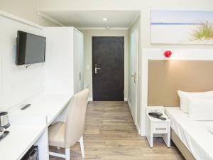 een kamer met een bed, een bureau en een deur bij Hotel Domicil Hamburg by Golden Tulip in Hamburg