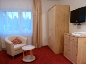een hotelkamer met een stoel en een televisie bij Landhaus Stümpelstal in Marburg an der Lahn