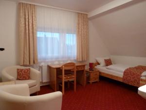 a hotel room with a bed and a desk and a window at Landhaus Stümpelstal in Marburg an der Lahn