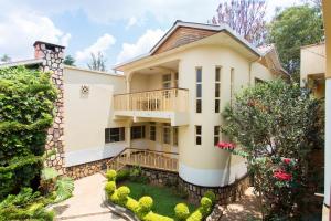 a large white house with a balcony and bushes at Iris Guest House in Kigali