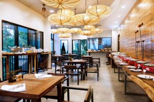 a restaurant with wooden tables and chairs and windows at Deevana Krabi Resort in Ao Nang Beach