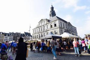 una multitud de personas caminando por un mercado frente a un edificio en De Hagendoorn, en Moorveld