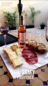 una bottiglia di vino, formaggio e carne su un tavolo di Les Jasmins a Saint-Rémy-de-Provence