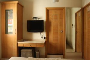ハイデラバードにあるHotel Stay Innのベッドルーム(デスク、テレビ、キャビネット付)