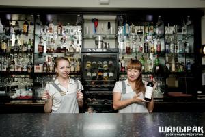 two girls standing behind a bar with a bottle of wine at Shanyrak Hotel in Temirtaū